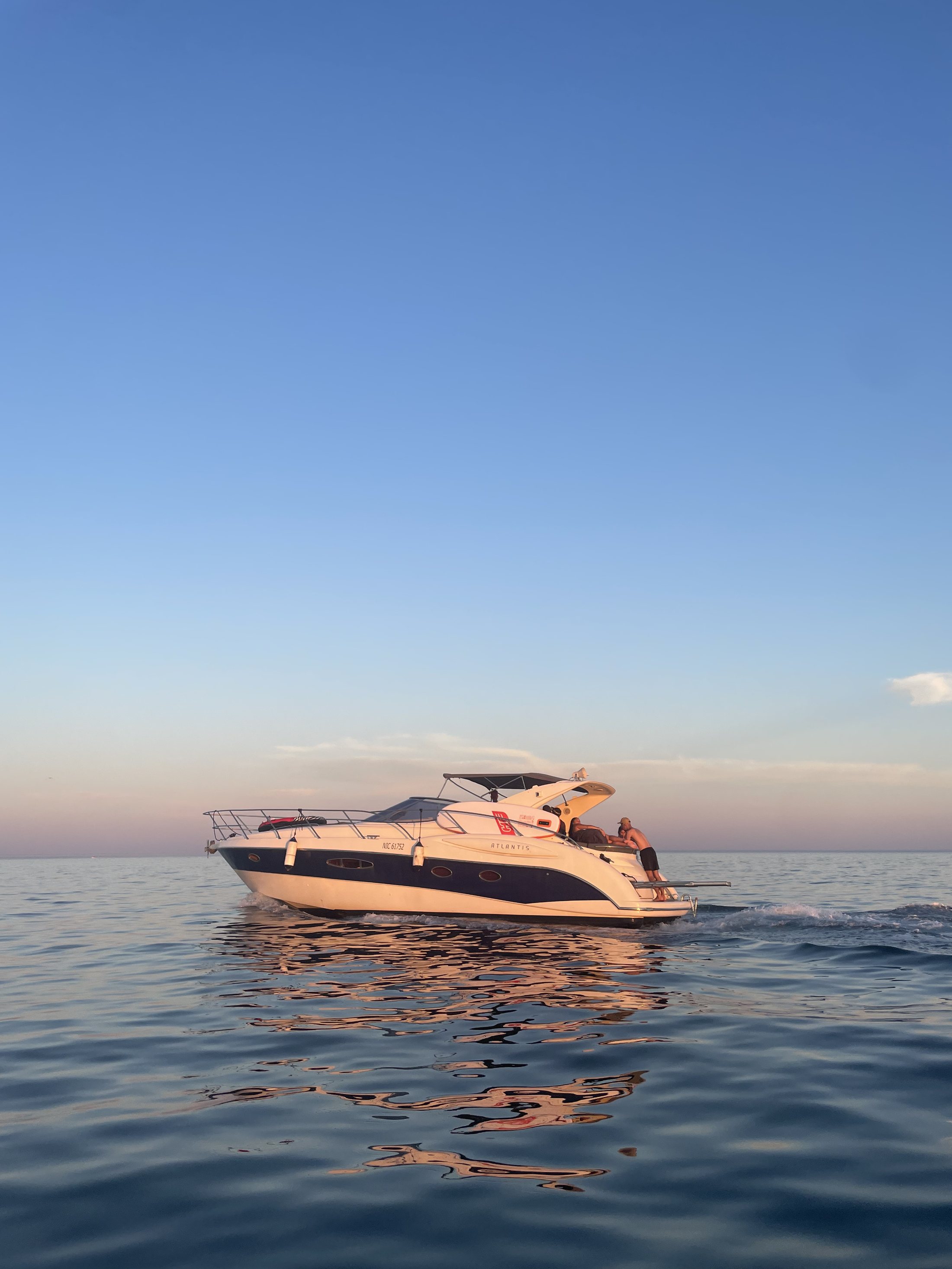 Le yacht Harmonie vu de loin au soleil couchant, reflets dorés sur une mer calme